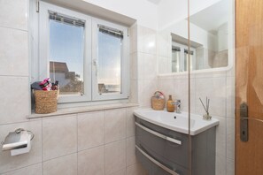Ein Badezimmer mit Fenster, Waschbecken, Spiegel und Handtuchhalter.