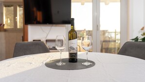 A bottle of wine and two glasses on a table with a view of a balcony. - Apartments Mari (Zadar)