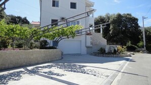 A two-story house with a garage, a staircase, and a paved driveway. - Apartments Mari (Zadar)
