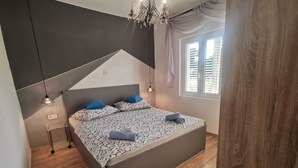 Un dormitorio moderno con una cama grande, una araña y una ventana con persianas.