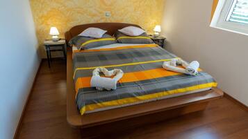 A neatly made bed with striped bedding, two bedside tables with lamps, and a window with blinds.