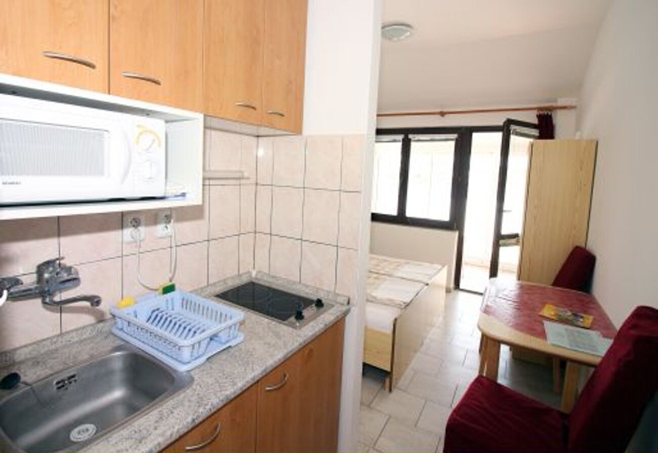 A compact kitchen with a microwave, sink, and a small dining area with a table and chairs.