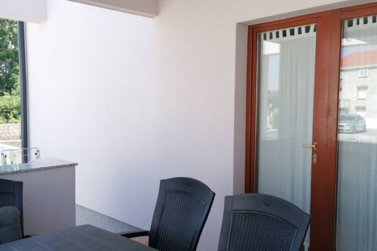 Un balcon avec une table et des chaises, une porte-fenêtre coulissante et une vue sur la rue.