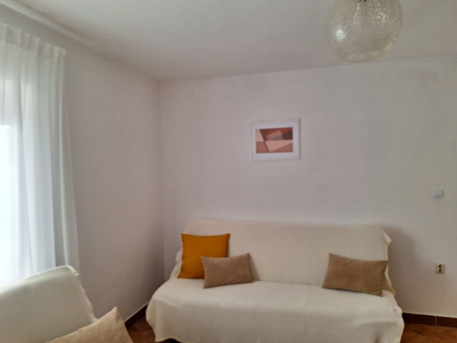 Un salon avec un canapé blanc, une petite table et un tableau accroché au mur.