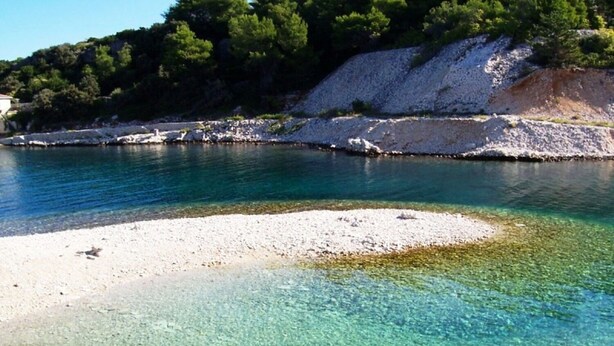 Una zona costera despejada con una playa de arena y un litoral rocoso.
