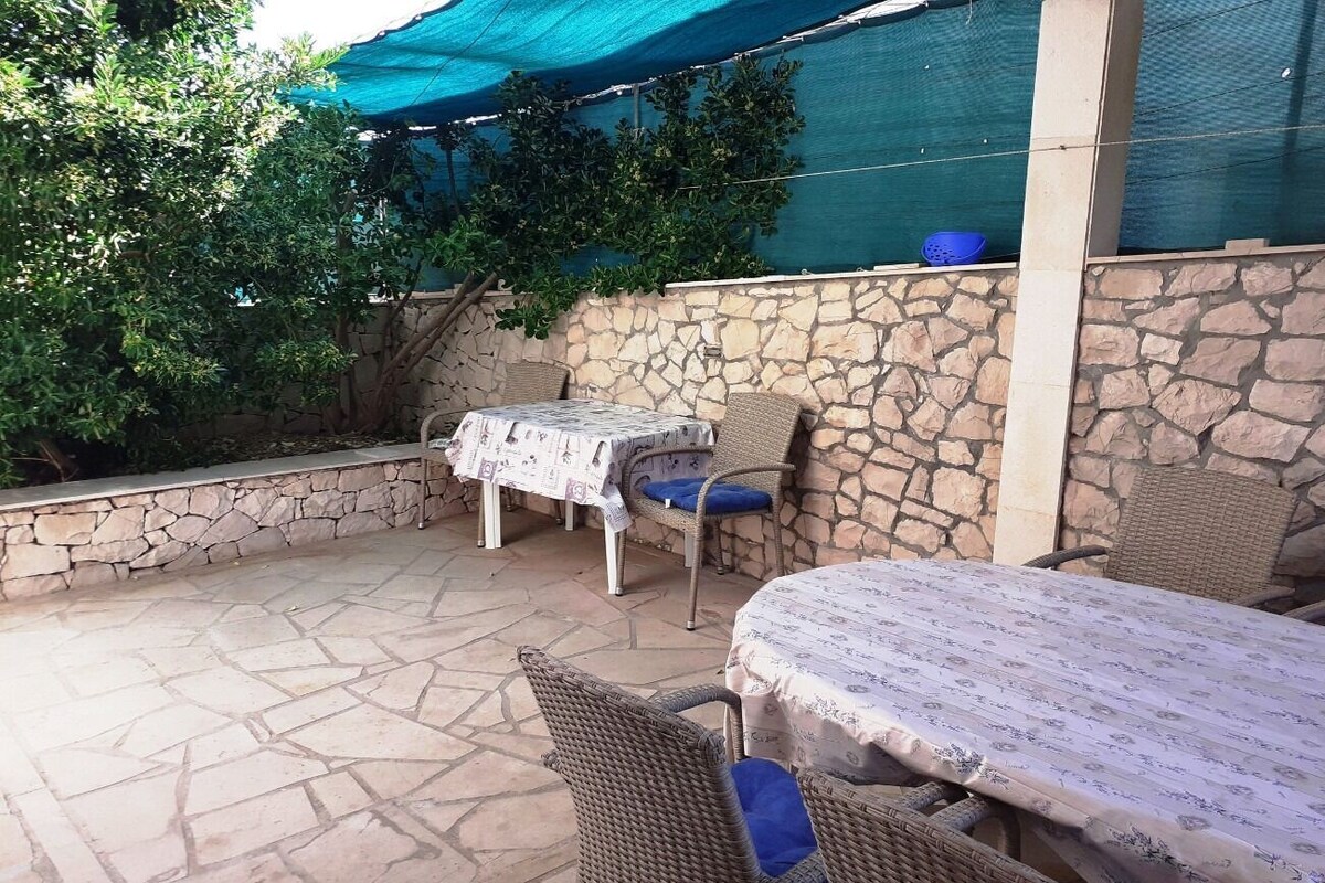 An outdoor patio with stone flooring, wicker furniture, and a table covered with a floral tablecloth.