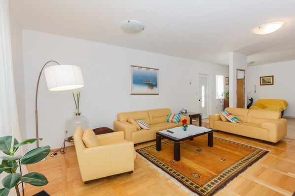 A living room with two beige sofas, a coffee table, a lamp, and a painting on the wall. - House Sanda (Supetar)