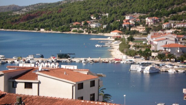Un pueblo costero con edificios, un puerto deportivo y barcos.