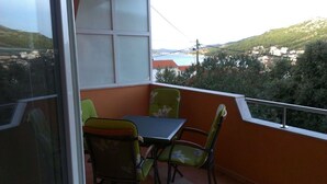 Un balcón con mesa y sillas, con vistas panorámicas a colinas y una masa de agua.