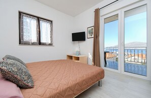 Une chambre à coucher avec un lit, une télévision, une fenêtre avec des rideaux et une vue sur le paysage urbain.
