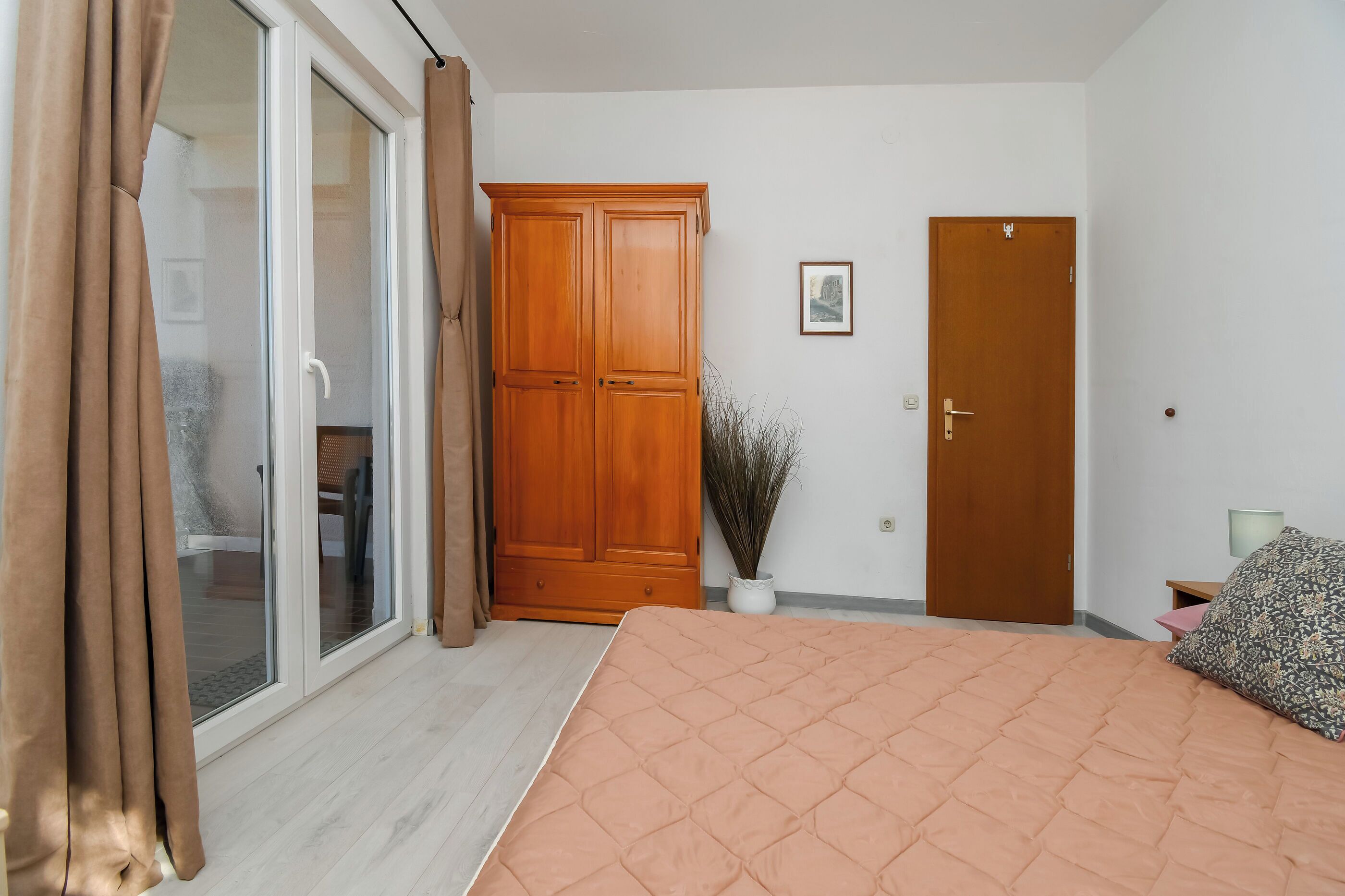 A bedroom with a bed, a wardrobe, a door, and a window with curtains.