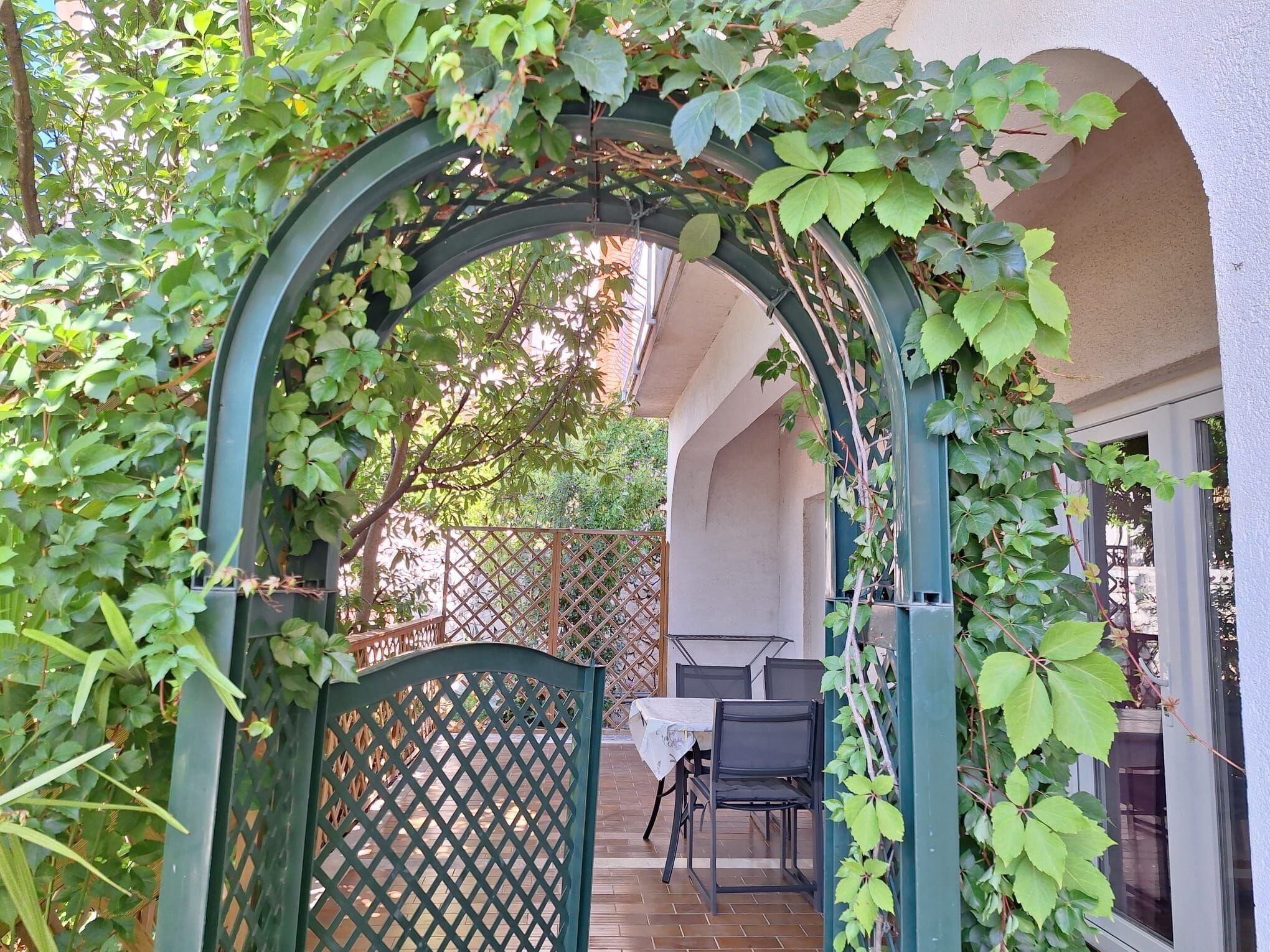 Ein möblierter Patio mit überdachtem Sitzbereich, einem Holztisch und Stühlen.