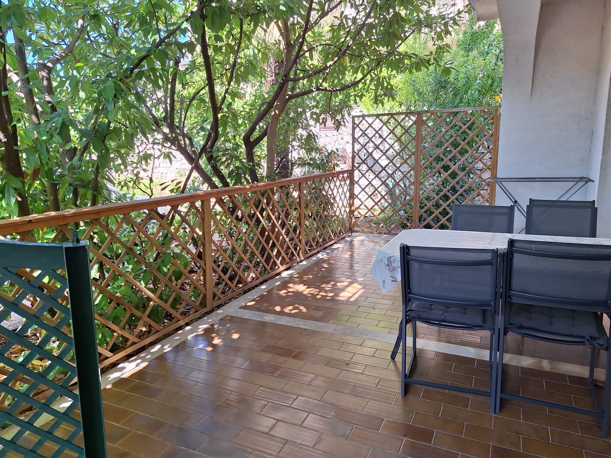 A patio with a wooden fence, a table, and chairs.