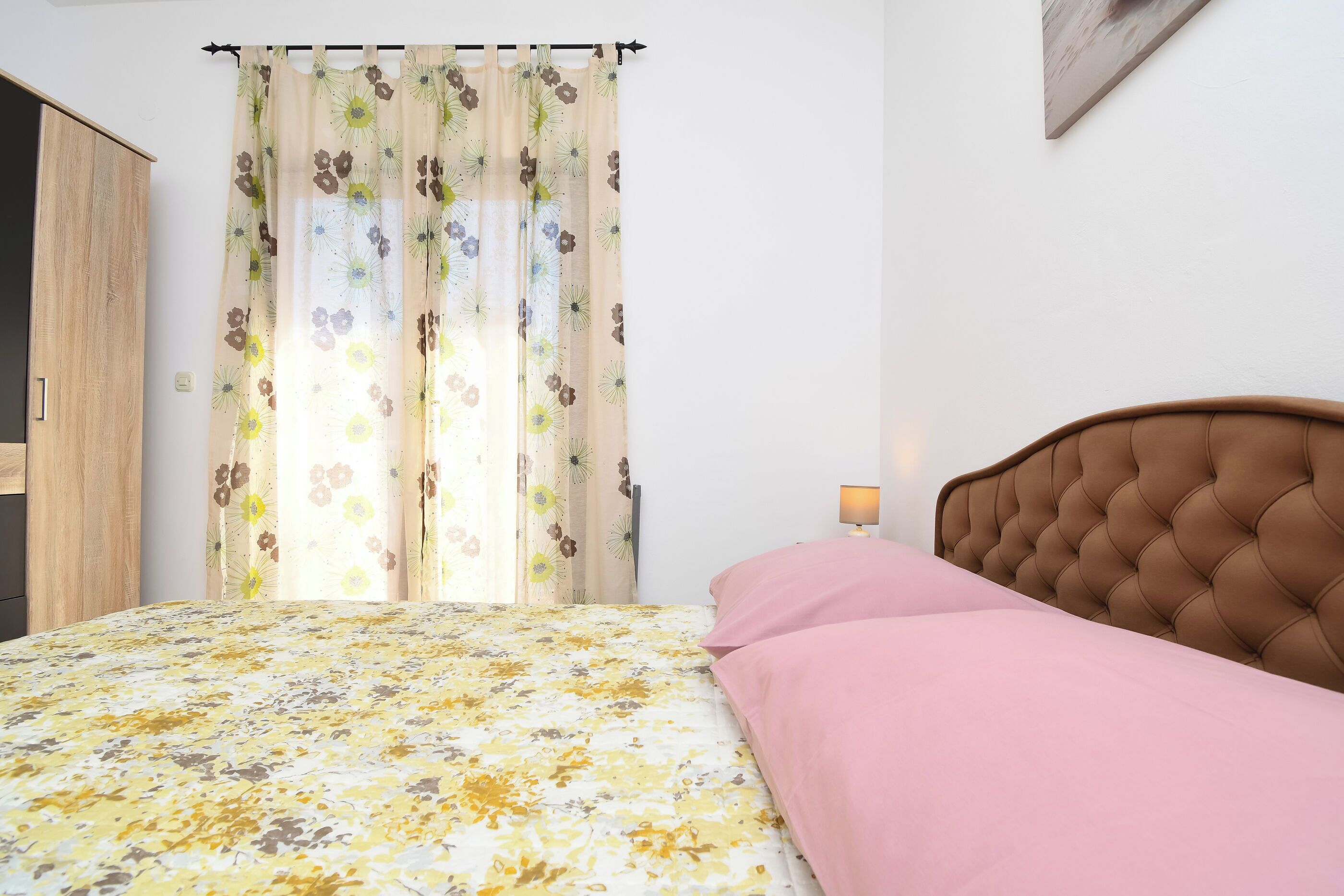 A bedroom with a bed, a headboard, a nightstand, and a wardrobe.