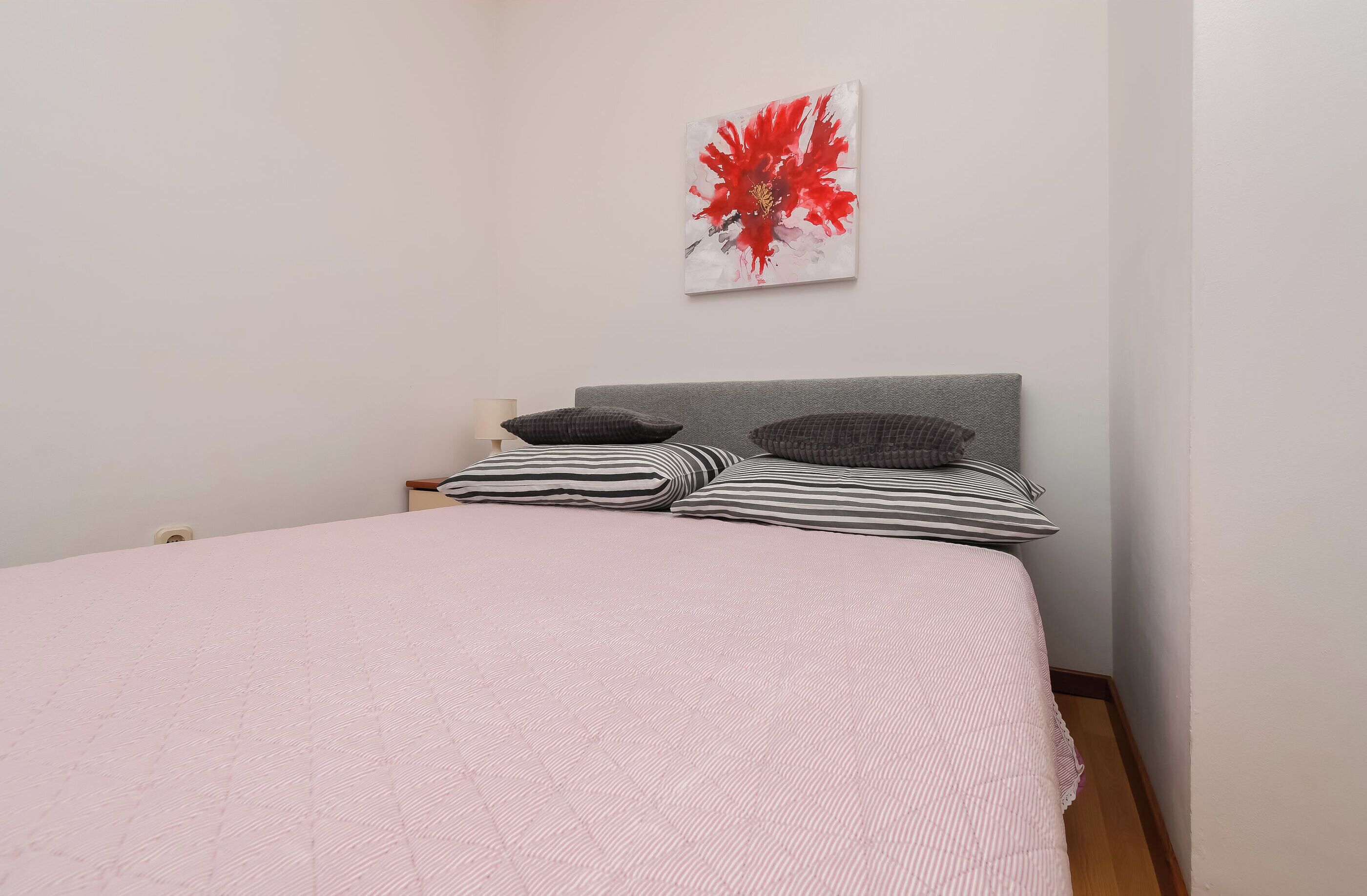 Une chambre à coucher avec un lit, une tête de lit et une œuvre d’art accrochée au mur.