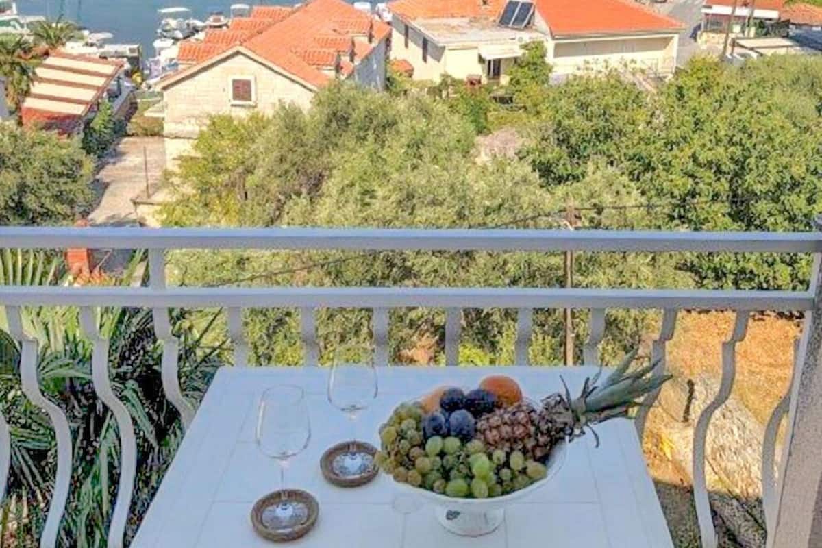 A balcony with a table set for two, overlooking a marina with boats and houses.