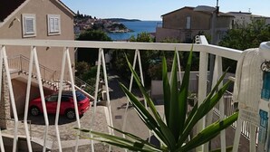 Ein Balkon mit Blick auf ein rotes Auto auf der Auffahrt, einen weißen Zaun und eine Pflanze im Vordergrund.