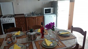 A kitchen with a stove, microwave, sink, and wooden cabinets. - Apartments Neva (Primosten)