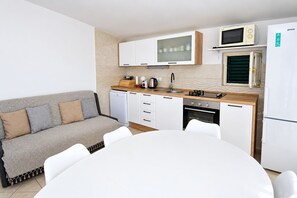 A compact kitchen with a built-in oven, microwave, and a small refrigerator. - Apartments Neva (Primosten)