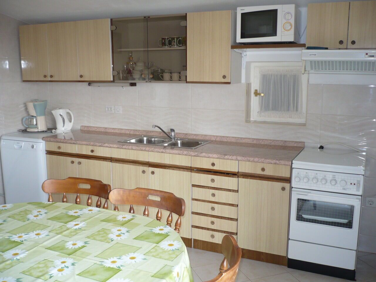 A compact kitchen with wooden cabinets, a microwave, a stove, and a sink.