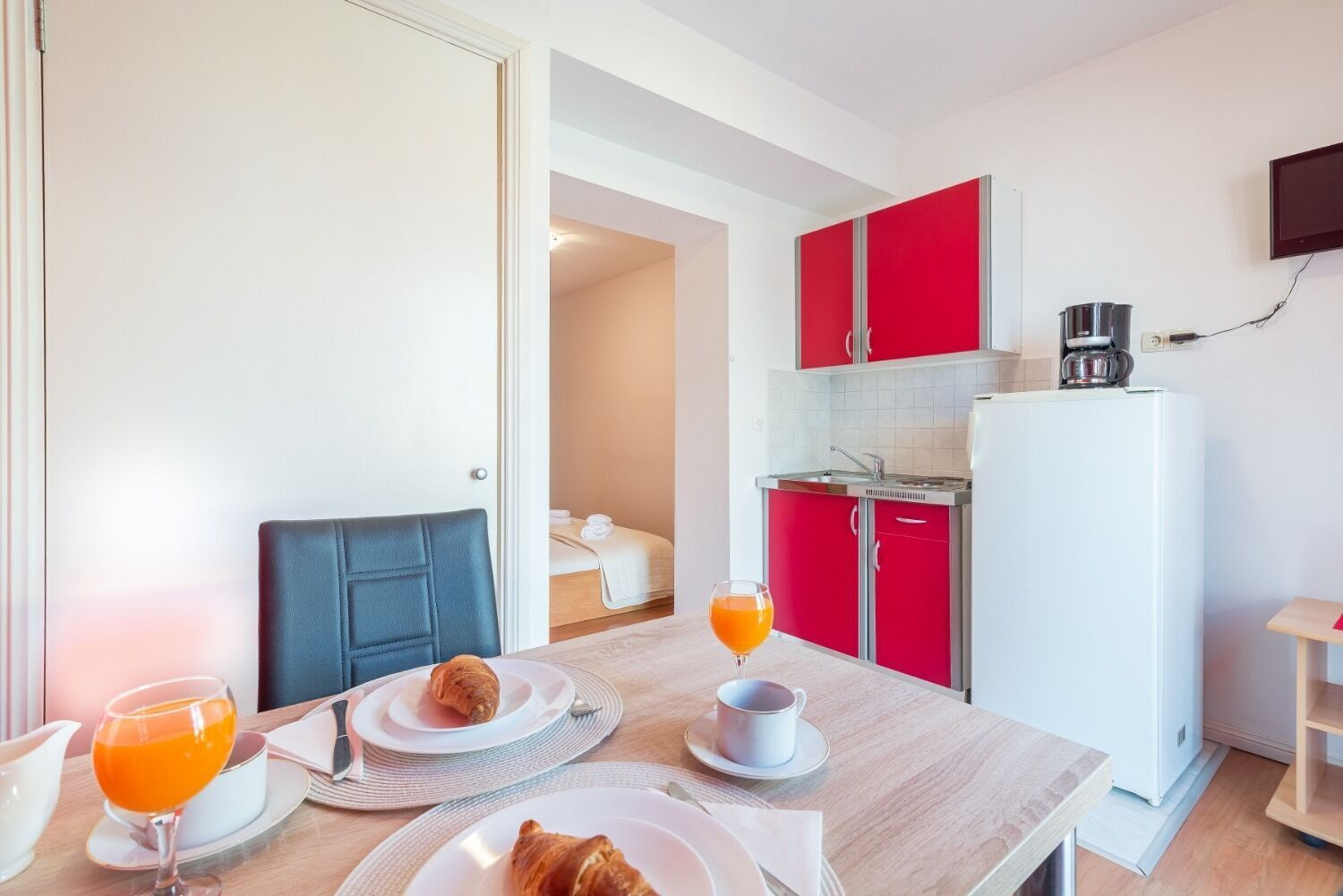 Une chambre d’hôtel compacte comprenant un coin repas, une kitchenette et un lit.