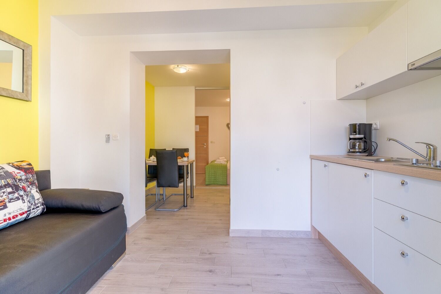Ein kompakter Wohnraum mit Küchenzeile, Essbereich und einem Bett.