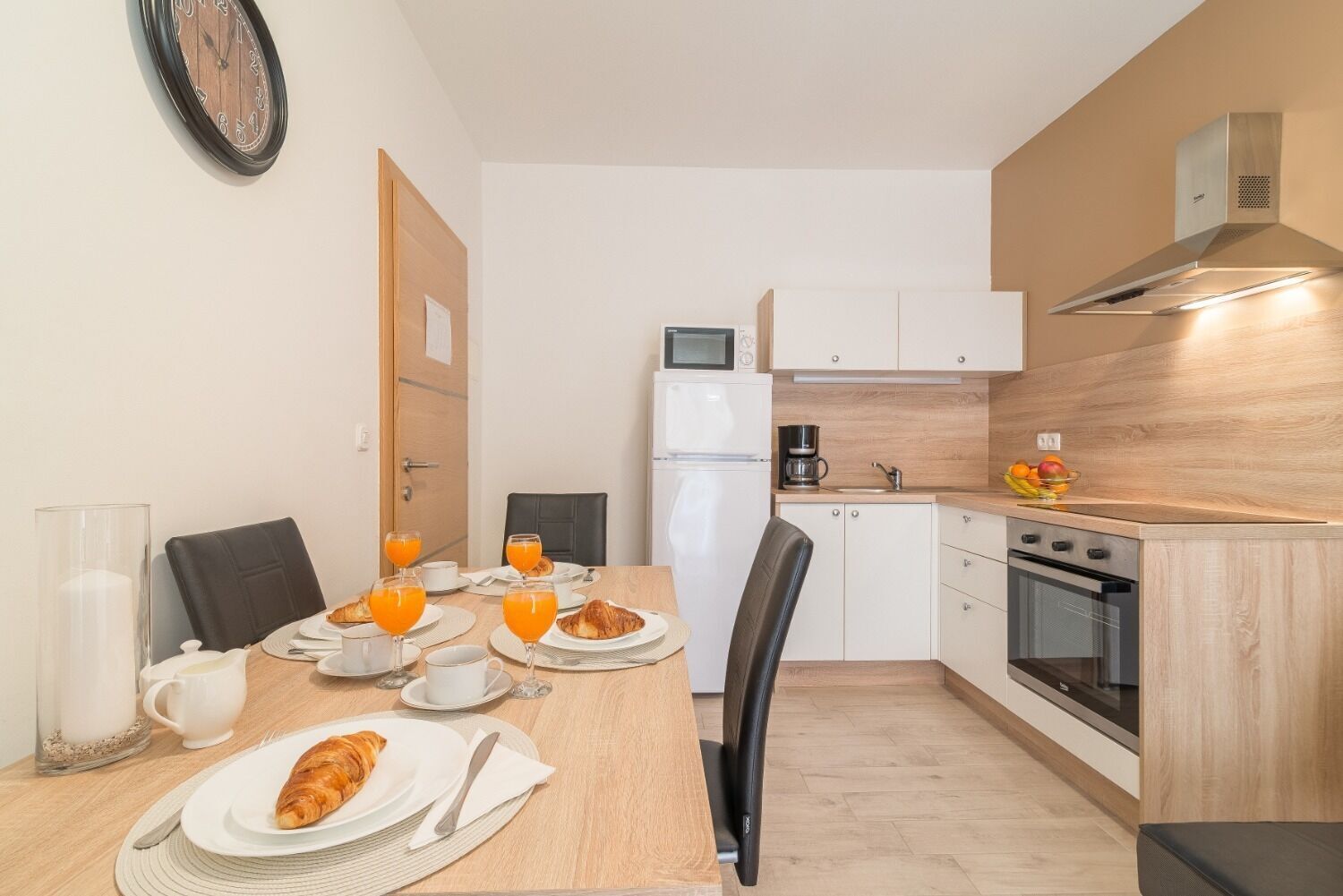 A compact kitchen with a dining table set for breakfast, a microwave, a coffee maker, and a stove.