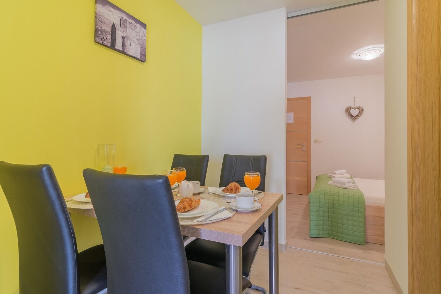 Ein Essbereich mit einem Tisch, der für ein Frühstück gedeckt ist, mit Croissants und Orangensaft.