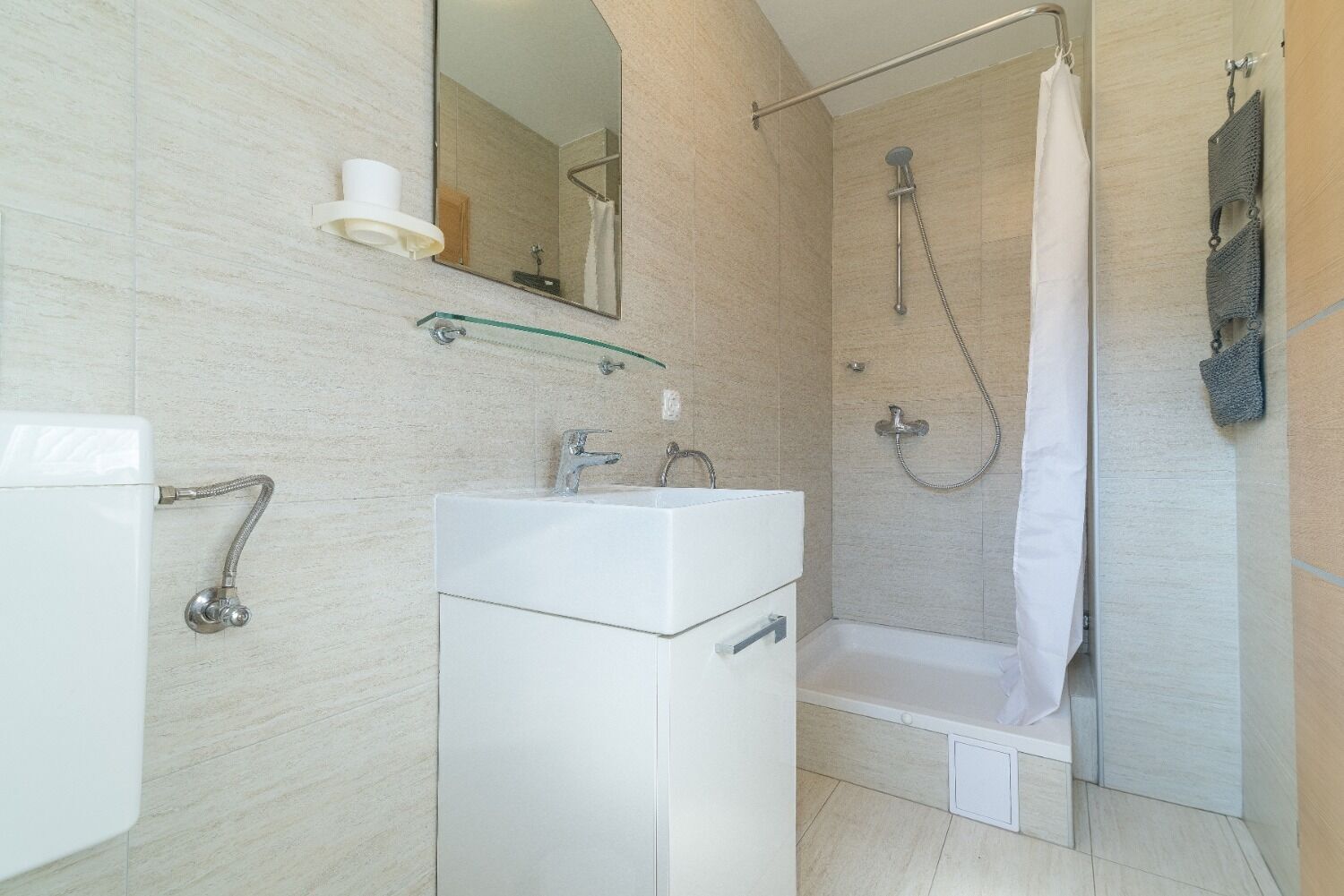 A modern bathroom with a glass shower enclosure, a white sink, and a mirror.