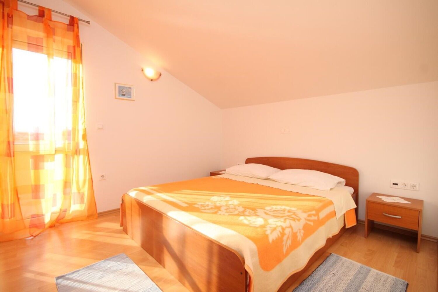 Ein Schlafzimmer mit Bett, Nachttisch und einem Fenster mit Vorhängen.