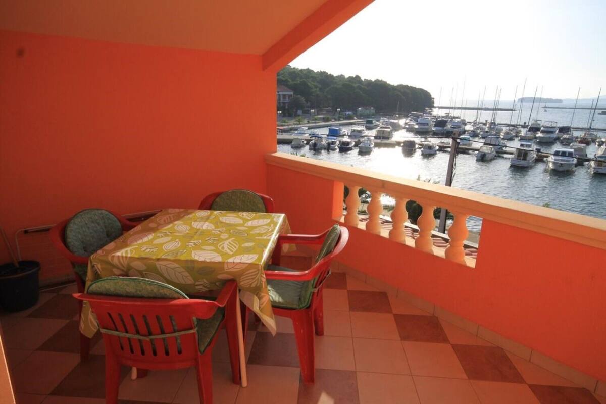A balcony with a table and chairs, overlooking a marina with boats.