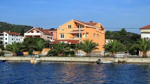 Un edificio sul lungomare con balconi, vista sull'acqua e palme.