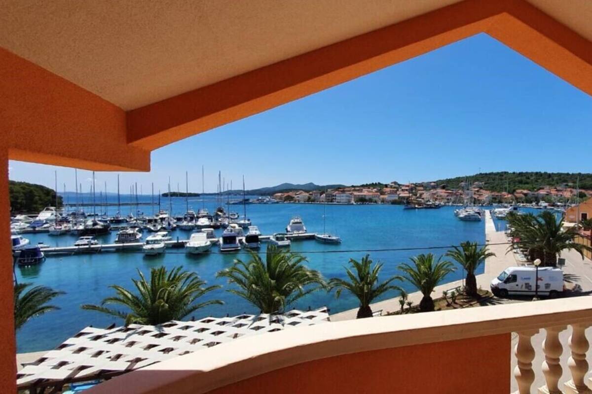 A balcony with a view of a marina, boats, and a coastal town.