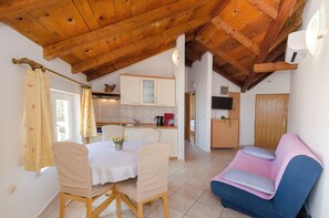 Eine gemütliche Küche mit Holzbalken, einem Essbereich mit Tisch und Stühlen und einem blauen Sofa.