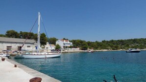 A marina with boats, a white building, and a clear blue sky. - Apartments Dragan (Tisno)