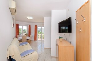 A living room with a sofa, TV, and a wooden cabinet. - Apartments Dragan (Tisno)