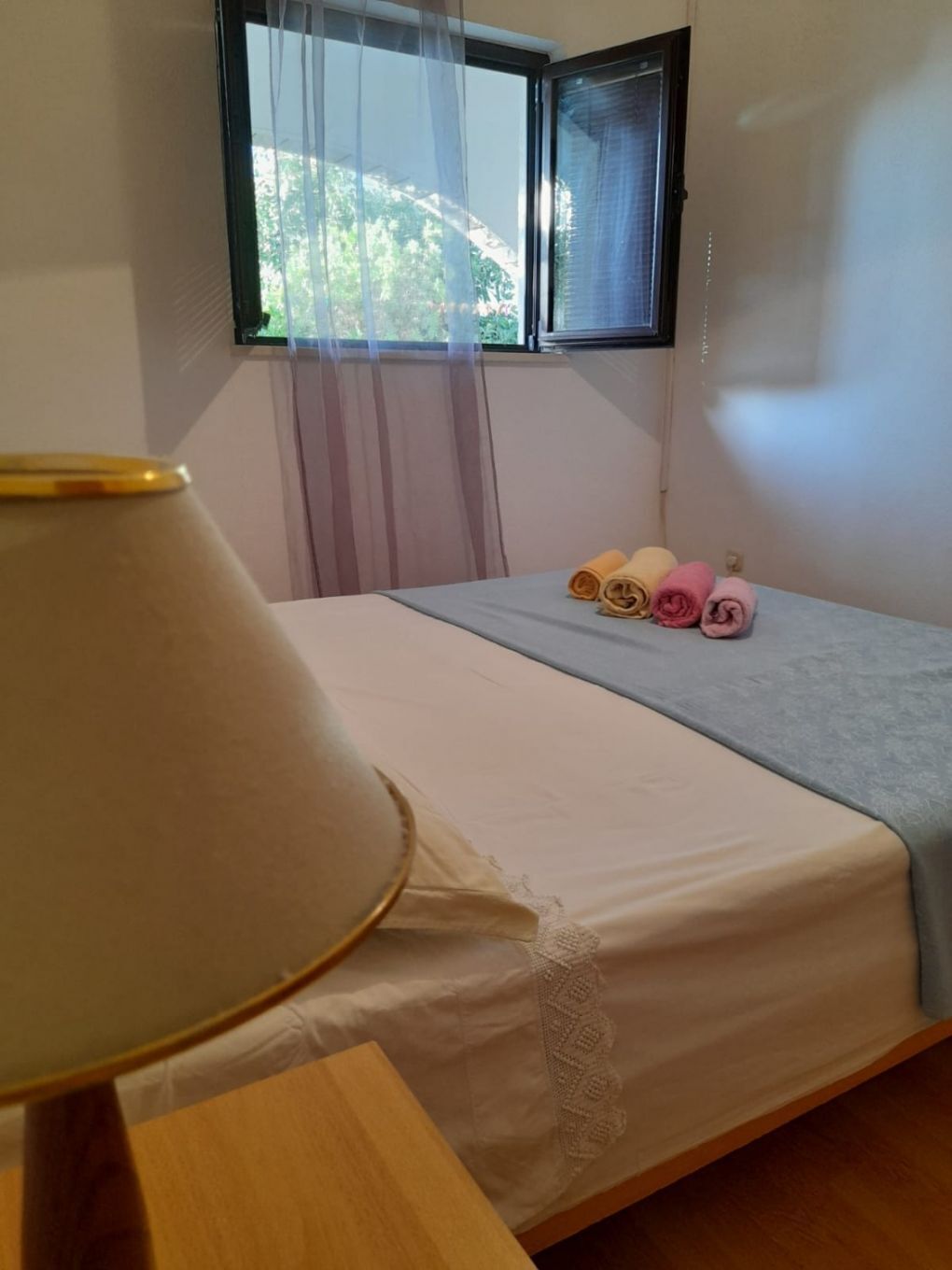 Ein Schlafzimmer mit einem Bett, einem Fenster mit Vorhängen und einer Lampe auf einem Nachttisch.