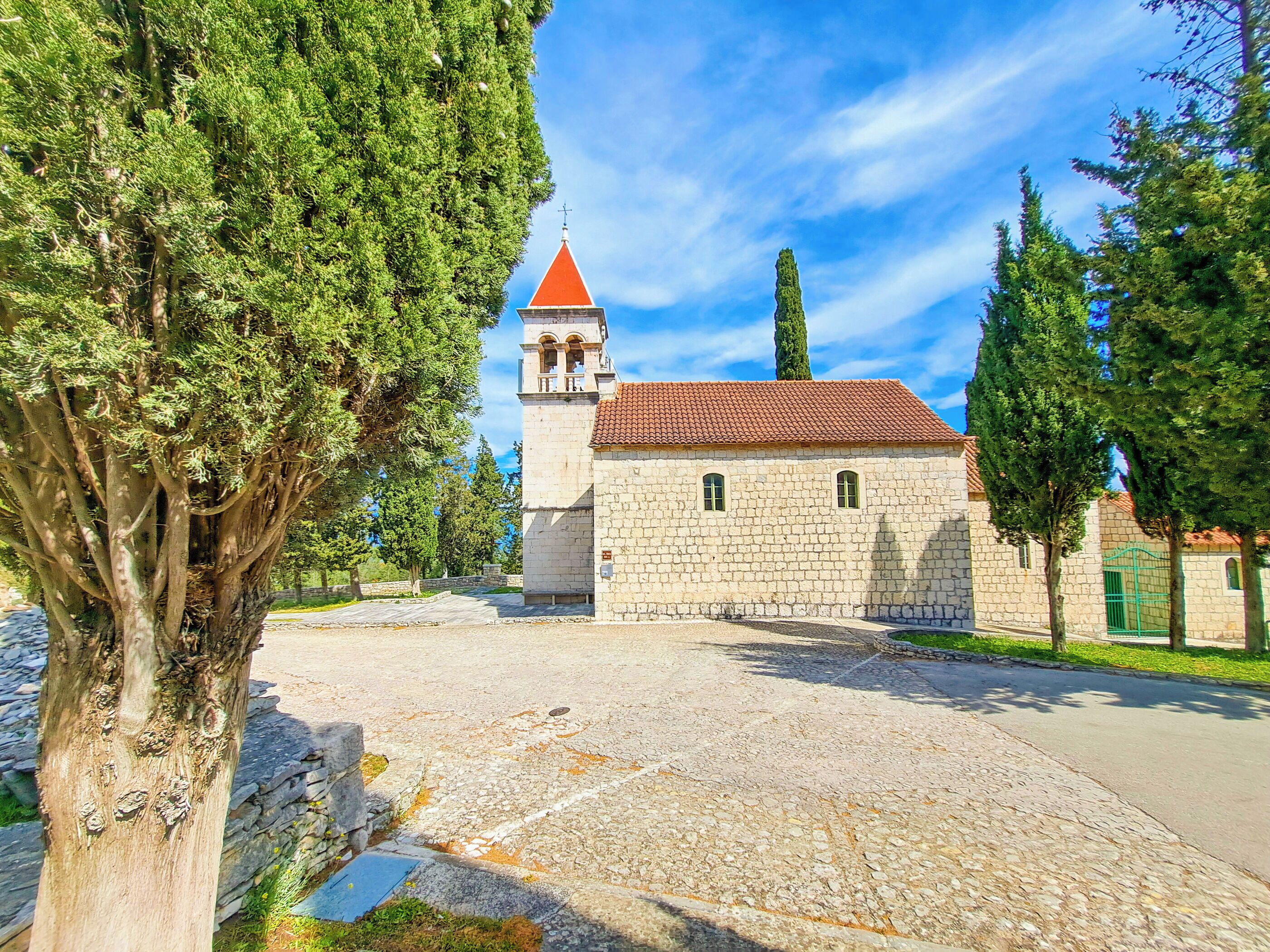 A stone building with a red-tiled roof and a bell tower.