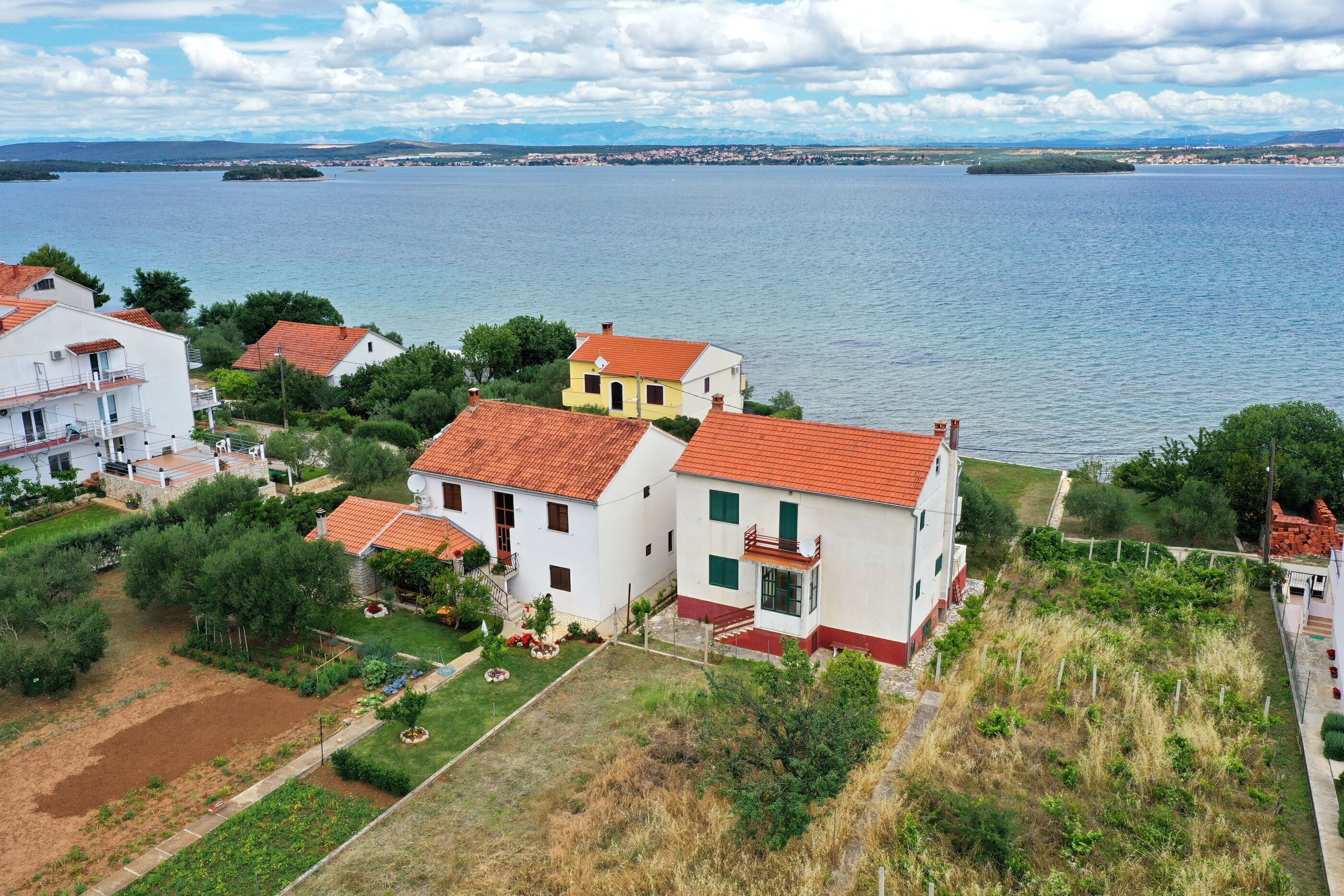 A coastal residential area with houses, a large body of water, and distant mountains.