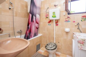 A bathroom with a beige sink, a toilet, a shower, and a window. - Apartments Suzi (Bol)