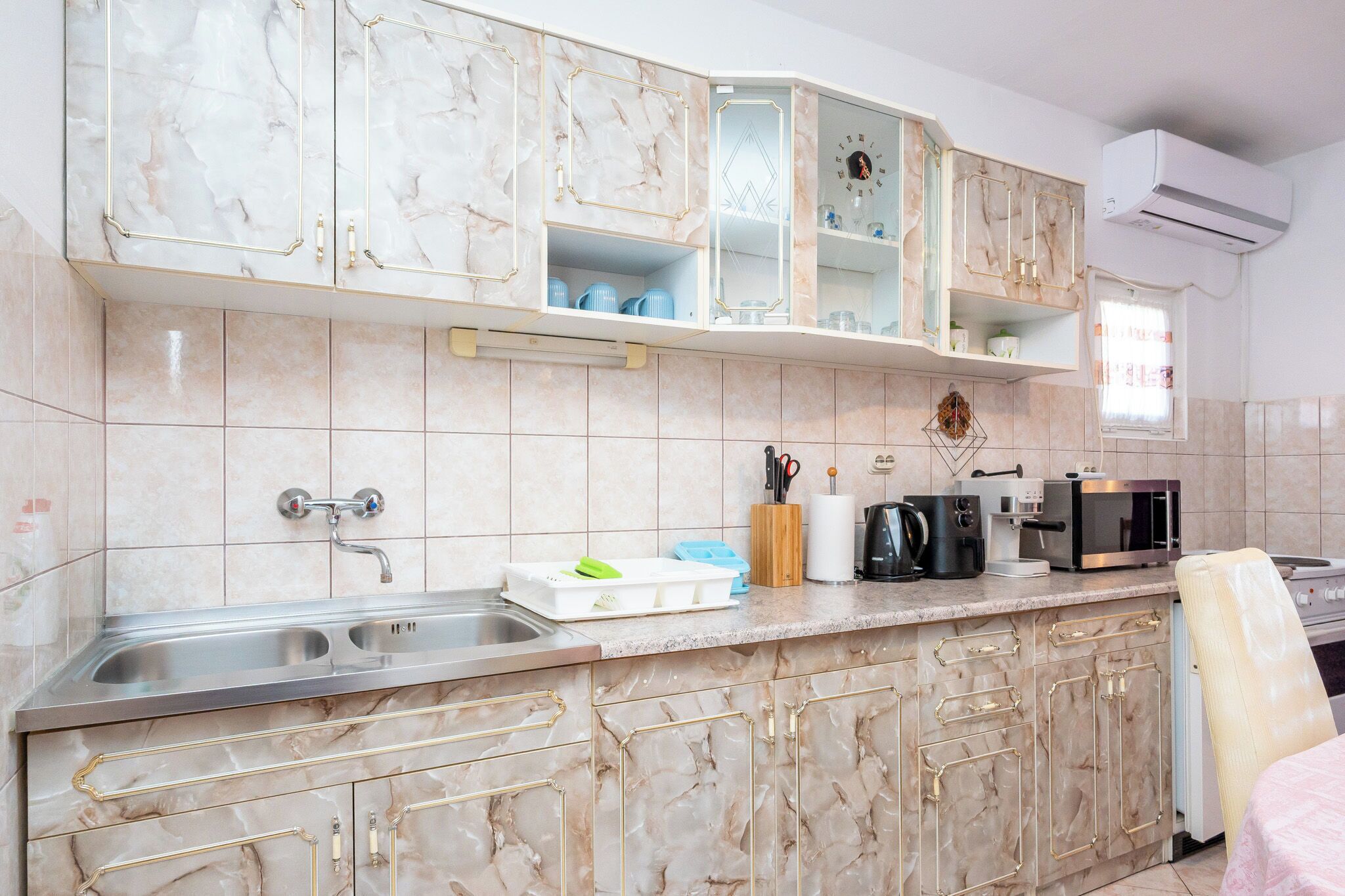 Cocina con armarios de mármol, un lavabo, un microondas y una cafetera.
