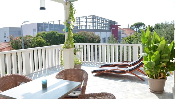 En tagterrasse med fletningsmøbler, et bord og krukker med planter.