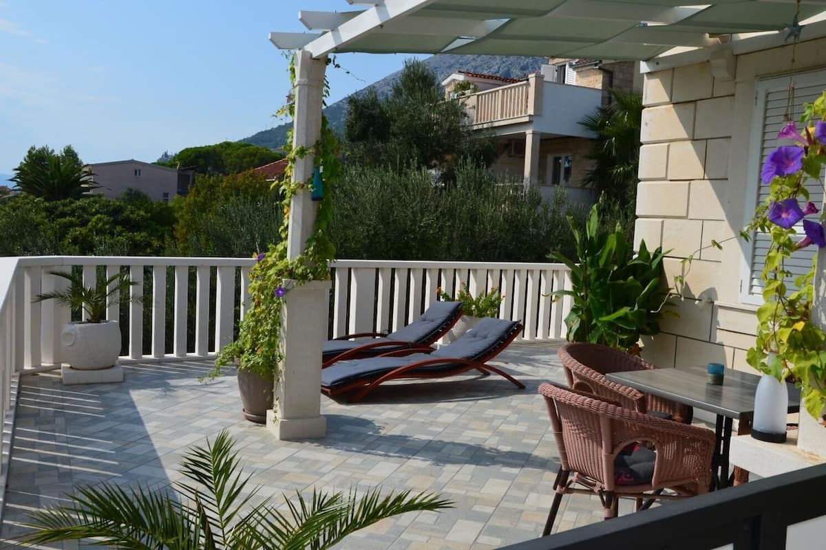 A balcony with sun loungers, a table, and potted plants.