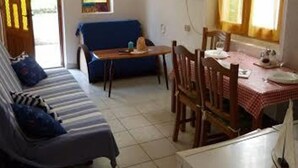 A compact living space with a sofa, dining table, chairs, a television, and a window with curtains. - House Kuca za Odmor (Preko)