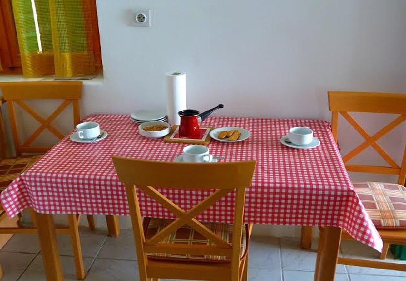 Una mesa de comedor con mantel a cuadros, dos sillas de madera, una olla roja y un plato blanco con comida.
