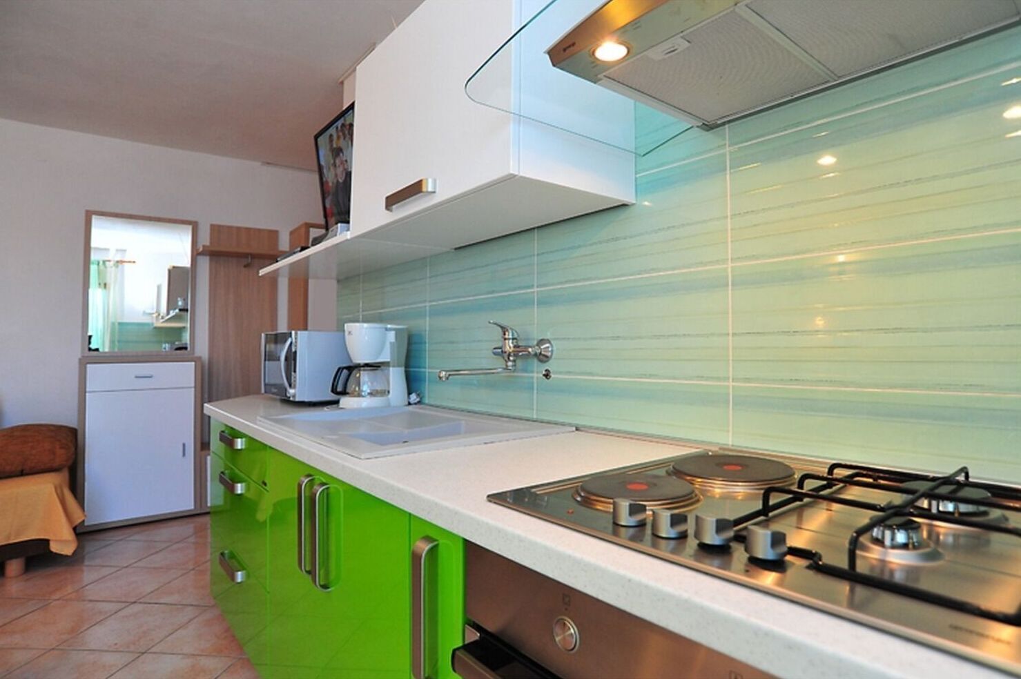 A compact kitchen with a gas stove, a coffee maker, and a small refrigerator.