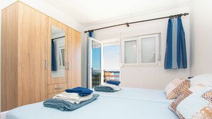 Une chambre à coucher avec un lit, une armoire, une fenêtre avec des rideaux et une vue sur l’extérieur.