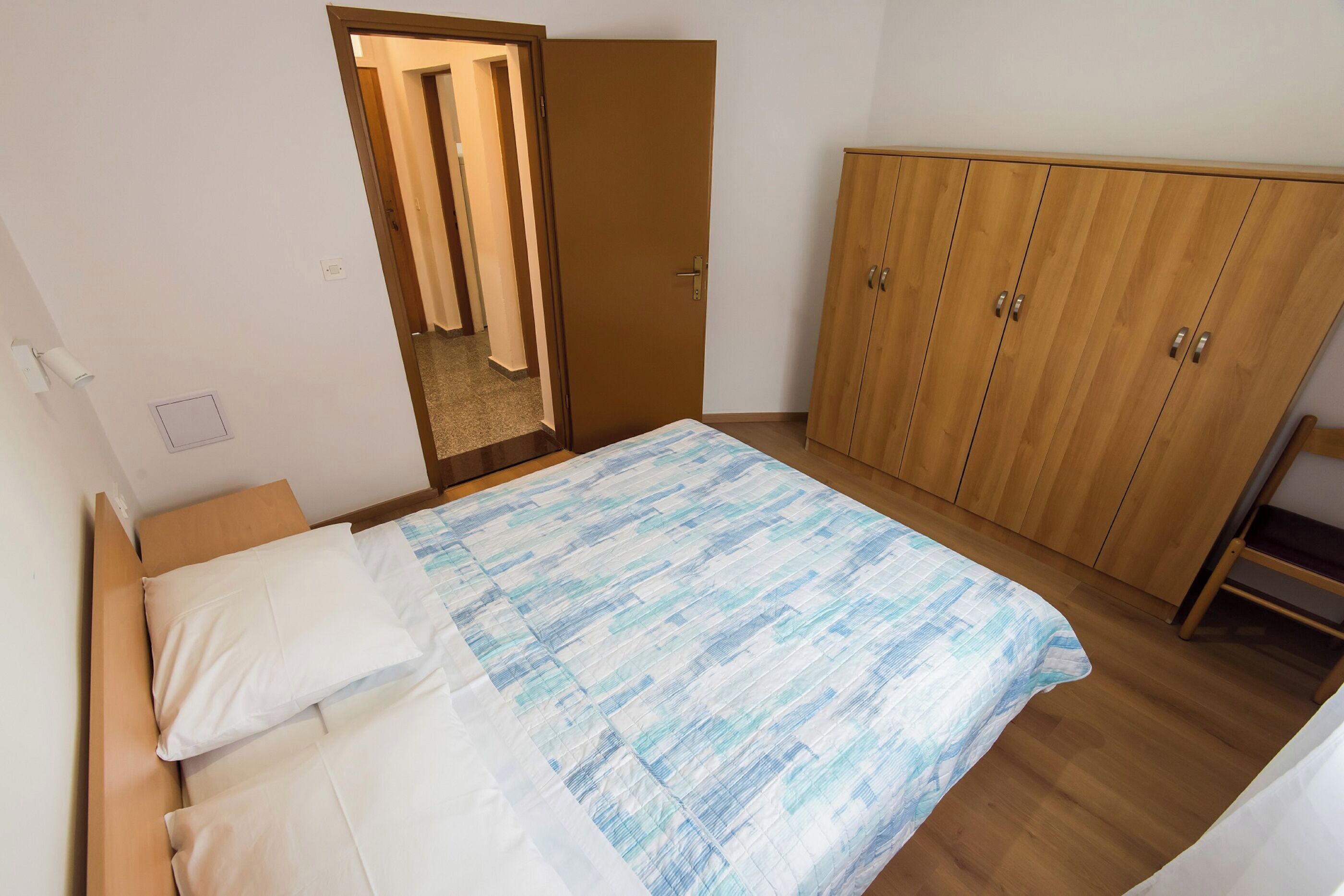 Una camera da letto con un letto, un'armadio in legno e una porta che dà su un'altra stanza.