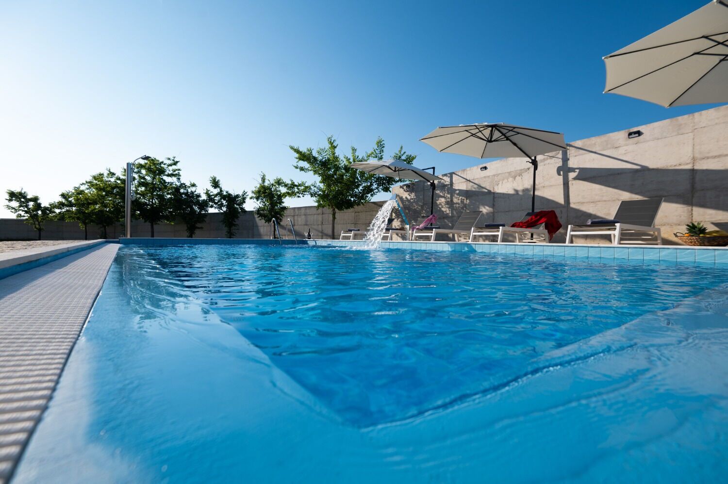 Outdoor pool, an infinity pool, pool umbrellas, pool loungers