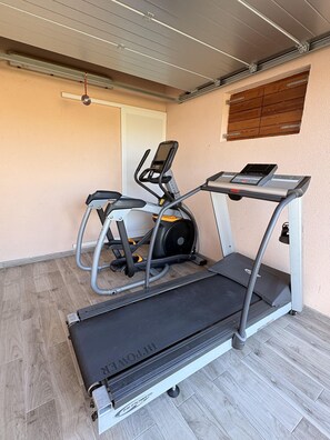 A home gym with a treadmill, elliptical, and stationary bike. - Apartments Armitage (Privlaka)